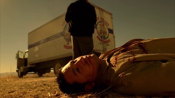 Movie still from “Breaking Bad” (2008), created by Vince Gilligan – A man laying on the ground in front of a truck; Medium shot, Low angle