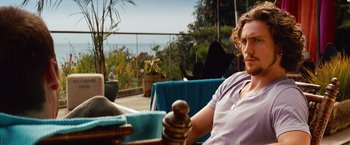 Movie still from “Savages” (2012), directed by Oliver Stone – A woman sitting on top of a chair in a room; Close Up shot, Over the shoulder angle