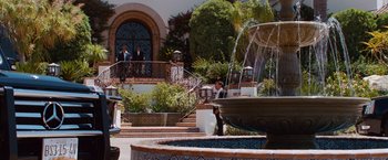 Movie still from “Savages” (2012), directed by Oliver Stone – Two men in suits are standing in front of a fountain; Extreme Wide shot, Over the shoulder angle