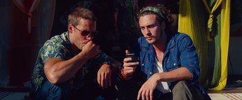 Movie still from “Savages” (2012), directed by Oliver Stone – Two young men sitting on the ground looking at a cell phone; Close Up shot, Low angle
