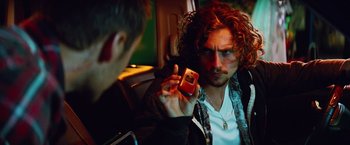 Movie still from “Savages” (2012), directed by Oliver Stone – A man holding up a cell phone while sitting in a car; Close Up shot, Over the shoulder angle