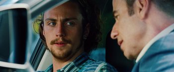 Movie still from “Savages” (2012), directed by Oliver Stone – A man with long hair is looking at the camera while another man looks at him; Close Up shot, Over the shoulder angle