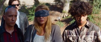 Movie still from “Savages” (2012), directed by Oliver Stone – A woman with a blindfold is standing next to a man; Medium shot, Over the shoulder angle