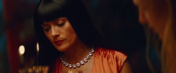 Movie still from “Savages” (2012), directed by Oliver Stone – A woman wearing a diamond necklace and a red dress; Close Up shot, Over the shoulder angle