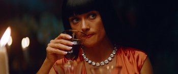 Movie still from “Savages” (2012), directed by Oliver Stone – A woman drinking a glass of wine at a party; Close Up shot, Over the shoulder angle
