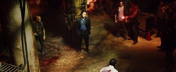 Movie still from “Savages” (2012), directed by Oliver Stone – A man in a suit standing in a dark room; Wide shot, High angle
