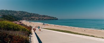 Movie still from “Savages” (2012), directed by Oliver Stone – People are walking their dogs along the beach; Extreme Wide shot, High angle