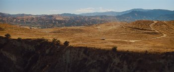 Movie still from “Savages” (2012), directed by Oliver Stone – A car is driving down a road in the middle of the desert; Extreme Wide shot, High angle