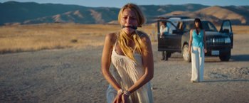 Movie still from “Savages” (2012), directed by Oliver Stone – A woman in a white dress is tied to a rope; Medium shot, Over the shoulder angle