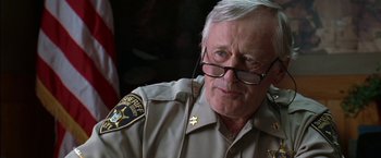 Movie still from “Secret Window” (2004), directed by David Koepp – An older man wearing a sheriff's uniform and glasses; Close Up shot, Over the shoulder angle