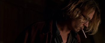 Movie still from “Secret Window” (2004), directed by David Koepp – A man with long blonde hair is standing in the dark; Close Up shot, Over the shoulder angle