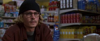 Movie still from “Secret Window” (2004), directed by David Koepp – A man with a hat and glasses sitting in front of a store; Close Up shot, Over the shoulder angle