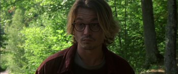 Movie still from “Secret Window” (2004), directed by David Koepp – A person wearing glasses with trees in the background; Close Up shot, Over the shoulder angle