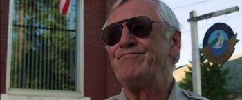 Movie still from “Secret Window” (2004), directed by David Koepp – An older man wearing sunglasses outside of a brick building; Close Up shot, Low angle