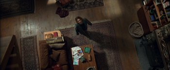 Movie still from “Secret Window” (2004), directed by David Koepp – A woman standing in a living room looking up at the floor; Extreme Wide shot, Overhead angle