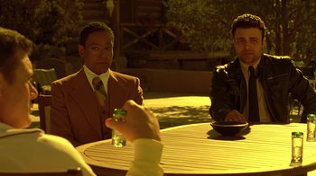 Movie still from “Breaking Bad” (2008), created by Vince Gilligan – Two men sitting at a table with a glass of water in front of them; Medium shot, Over the shoulder angle