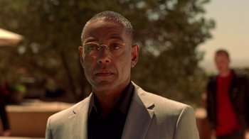 Movie still from “Breaking Bad” (2008), created by Vince Gilligan – A person wearing a suit and glasses; Close Up shot, Low angle
