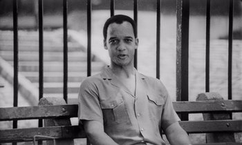 Movie still from “She's Gotta Have It” (1986), directed by Spike Lee – Black and white photograph of a man sitting on a bench; Close Up shot, Low angle