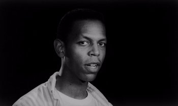 Movie still from “She's Gotta Have It” (1986), directed by Spike Lee – A black and white photo of a man in a white shirt; Close Up shot, Low angle