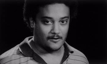 Movie still from “She's Gotta Have It” (1986), directed by Spike Lee – A black and white photo of a man in a striped shirt; Close Up shot, High angle