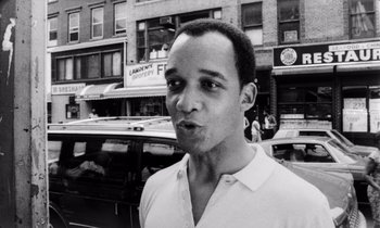 Movie still from “She's Gotta Have It” (1986), directed by Spike Lee – Black and white photograph of a man in front of a building; Close Up shot, Low angle