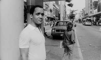 Movie still from “She's Gotta Have It” (1986), directed by Spike Lee – Black and white photograph of a man and a woman on the sidewalk; Medium shot, Low angle