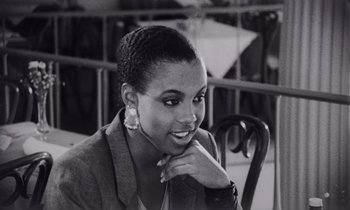 Movie still from “She's Gotta Have It” (1986), directed by Spike Lee – A black and white photo of a woman smiling; Close Up shot, Over the shoulder angle