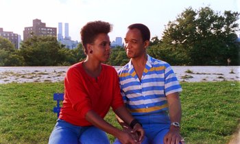 Movie still from “She's Gotta Have It” (1986), directed by Spike Lee – A man and a woman sitting next to each other on a park bench; Medium shot, Low angle