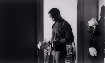 Movie still from “She's Gotta Have It” (1986), directed by Spike Lee – A black and white photo of a man holding a phone; Medium shot, Low angle