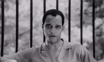 Movie still from “She's Gotta Have It” (1986), directed by Spike Lee – Black and white photograph of a man in front of a fence; Close Up shot, Low angle