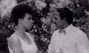 Movie still from “She's Gotta Have It” (1986), directed by Spike Lee – A man and a woman standing next to each other in front of a tree; Close Up shot, Low angle