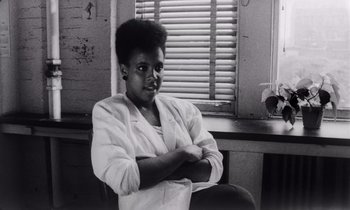 Movie still from “She's Gotta Have It” (1986), directed by Spike Lee – A black and white photo of a woman sitting in front of a window; Close Up shot, Low angle