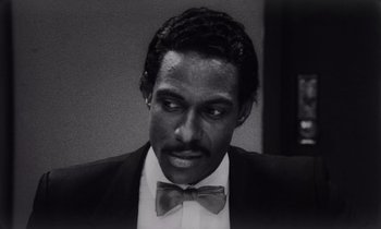Movie still from “She's Gotta Have It” (1986), directed by Spike Lee – A black and white photo of a man wearing a suit and bow tie; Close Up shot, High angle