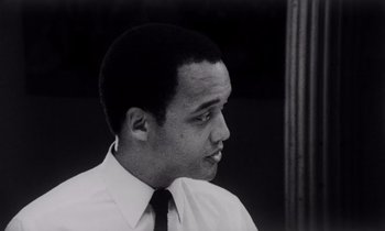 Movie still from “She's Gotta Have It” (1986), directed by Spike Lee – A black and white photo of a man wearing a shirt and tie; Close Up shot, Low angle