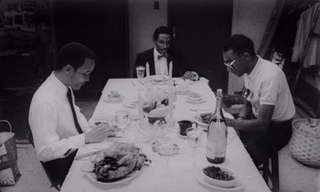 Movie still from “She's Gotta Have It” (1986), directed by Spike Lee – A group of men sitting at a dinner table; Medium shot, High angle