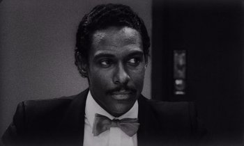 Movie still from “She's Gotta Have It” (1986), directed by Spike Lee – A black and white photo of a man in a suit and bow tie; Close Up shot, Low angle