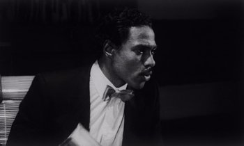 Movie still from “She's Gotta Have It” (1986), directed by Spike Lee – A black and white photo of a man wearing a bow tie; Close Up shot, Low angle