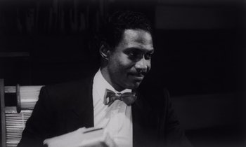 Movie still from “She's Gotta Have It” (1986), directed by Spike Lee – A black and white photo of a man wearing a suit and bow tie; Close Up shot, Low angle