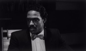 Movie still from “She's Gotta Have It” (1986), directed by Spike Lee – Black and white photograph of a man in a suit and bow tie; Close Up shot, Low angle