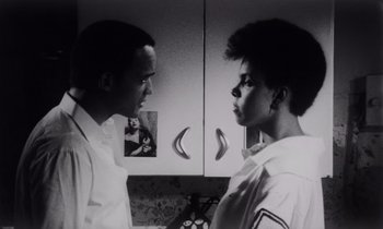 Movie still from “She's Gotta Have It” (1986), directed by Spike Lee – Two people standing next to each other in front of a cabinet; Close Up shot, Low angle