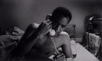 Movie still from “She's Gotta Have It” (1986), directed by Spike Lee – A man sitting on a bed talking on a phone; Close Up shot, High angle