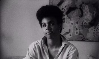 Movie still from “She's Gotta Have It” (1986), directed by Spike Lee – A black and white photo of a woman in front of a painting; Close Up shot, Low angle