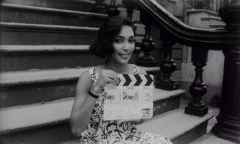 Movie still from “She's Gotta Have It” (1986), directed by Spike Lee – Black and white photograph of a woman holding a clapperboard; Close Up shot, High angle