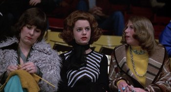 Movie still from “Slap Shot” (1977), directed by George Roy Hill – A woman in a black and white striped dress; Medium shot, Low angle