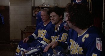 Movie still from “Slap Shot” (1977), directed by George Roy Hill – A group of men sitting next to each other on a bench; Medium shot, Low angle
