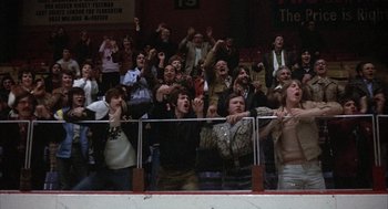 Movie still from “Slap Shot” (1977), directed by George Roy Hill – A group of people standing in the stands at a basketball game; Wide shot, High angle