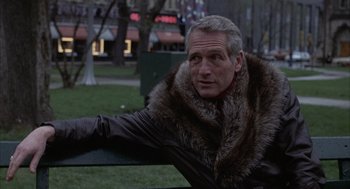 Movie still from “Slap Shot” (1977), directed by George Roy Hill – A man sitting on top of a park bench wearing a fur coat; Close Up shot, Over the shoulder angle