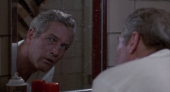 Movie still from “Slap Shot” (1977), directed by George Roy Hill – A man looking at himself in the mirror in front of a bathroom mirror; Close Up shot, Over the shoulder angle