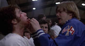 Movie still from “Slap Shot” (1977), directed by George Roy Hill – A man is being shaved by another man in front of a group of people; Close Up shot, Low angle