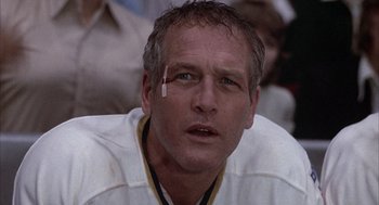 Movie still from “Slap Shot” (1977), directed by George Roy Hill – A person wearing a hockey uniform; Close Up shot, Low angle
